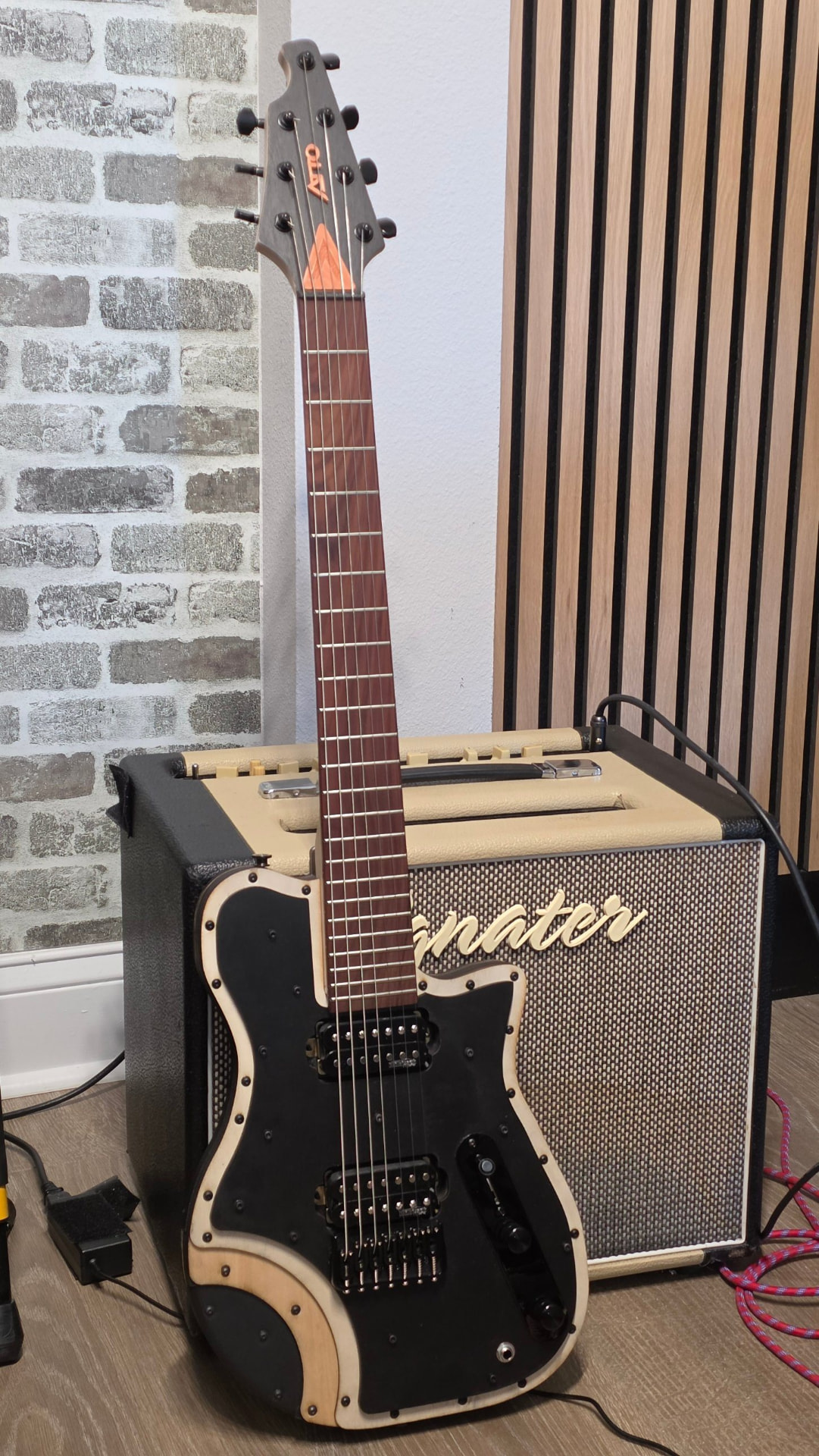 E75 LZR seven-string electric SieteQuinto standing in front of an amplifier
